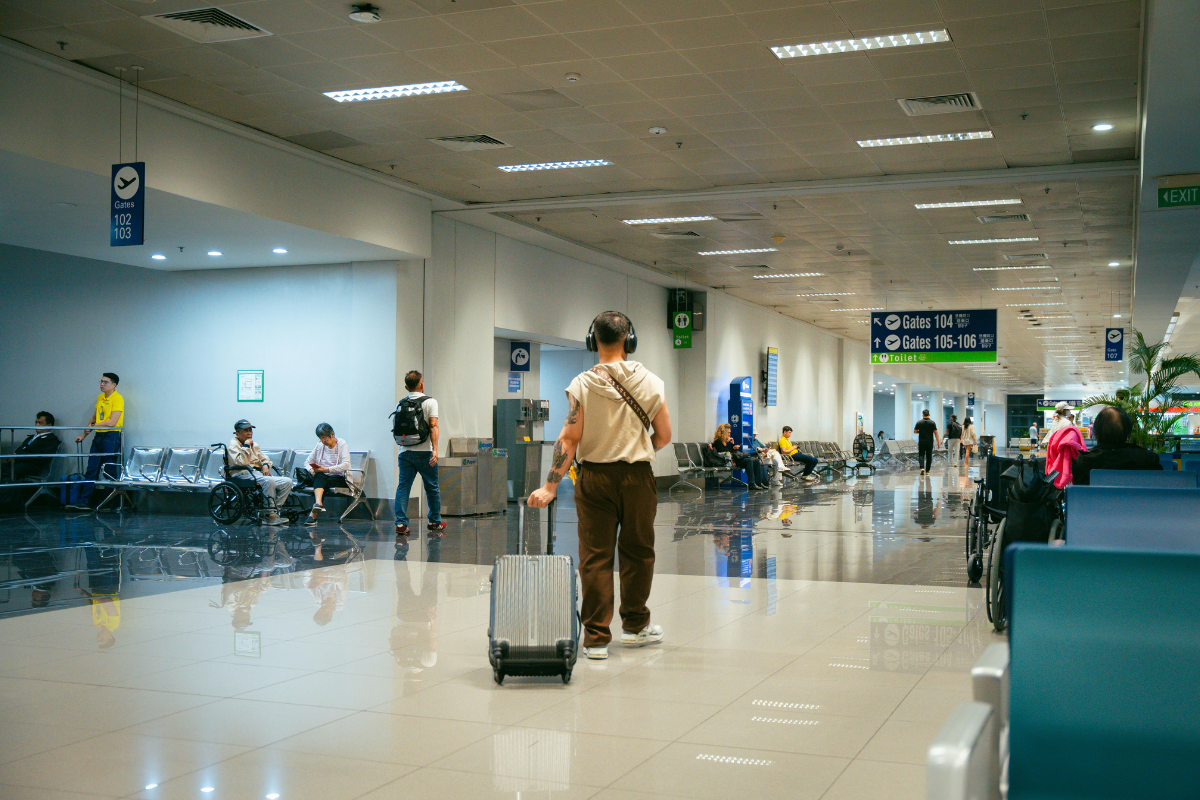 Travelers walking through a modern airport terminal with luggage.