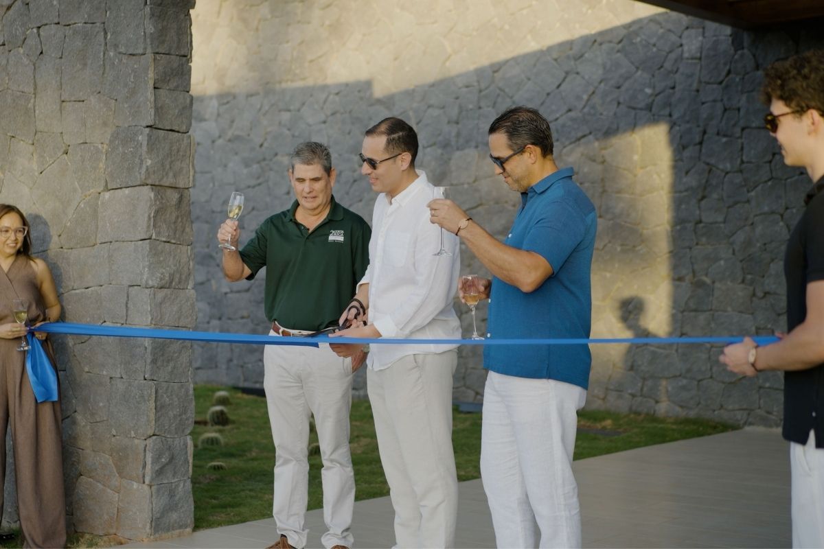 Men in white shirts and a man in a blue shirt performing a ribbon-cutting ceremony at the One Hacienda Pinilla development.