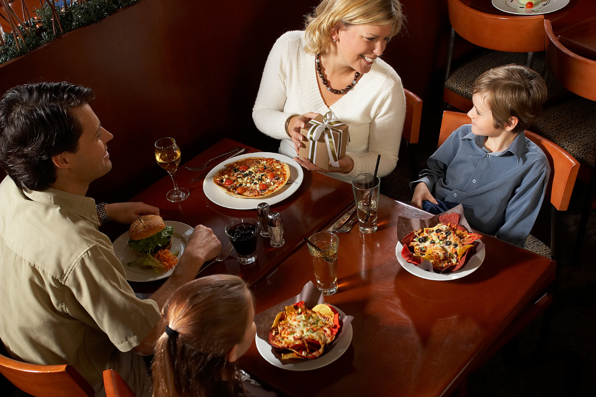 A family enjoying a meal together at a restaurant dining table, with food and drinks served.