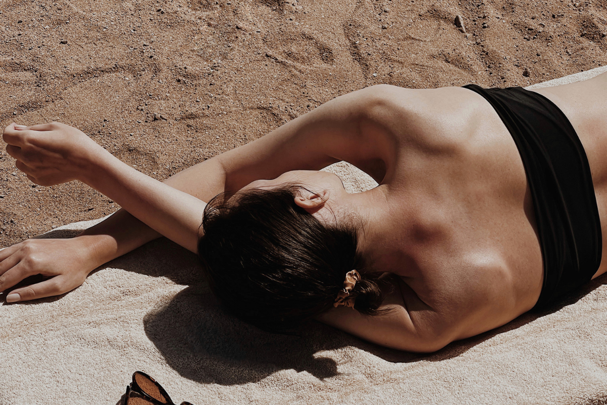 Woman sunbathing on a sandy beach in the sun, relaxing in the sun