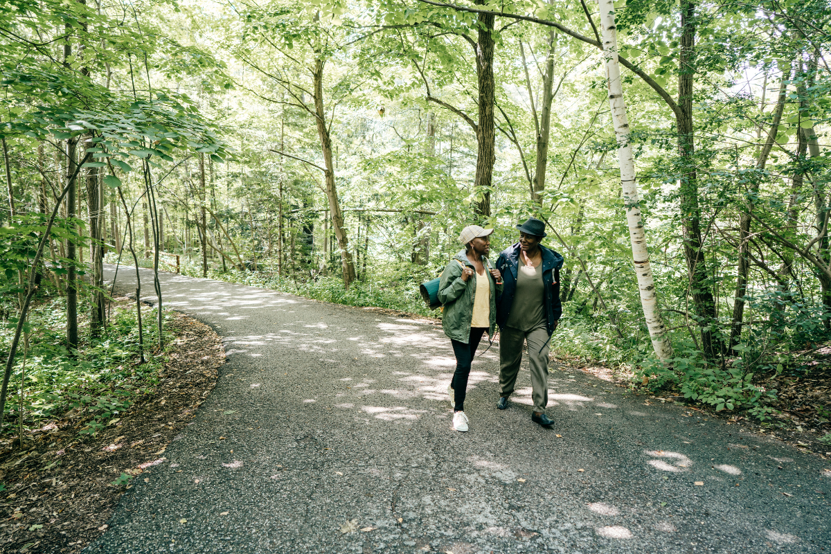 Couple walking together along a lush green tree-lined path in a gated community