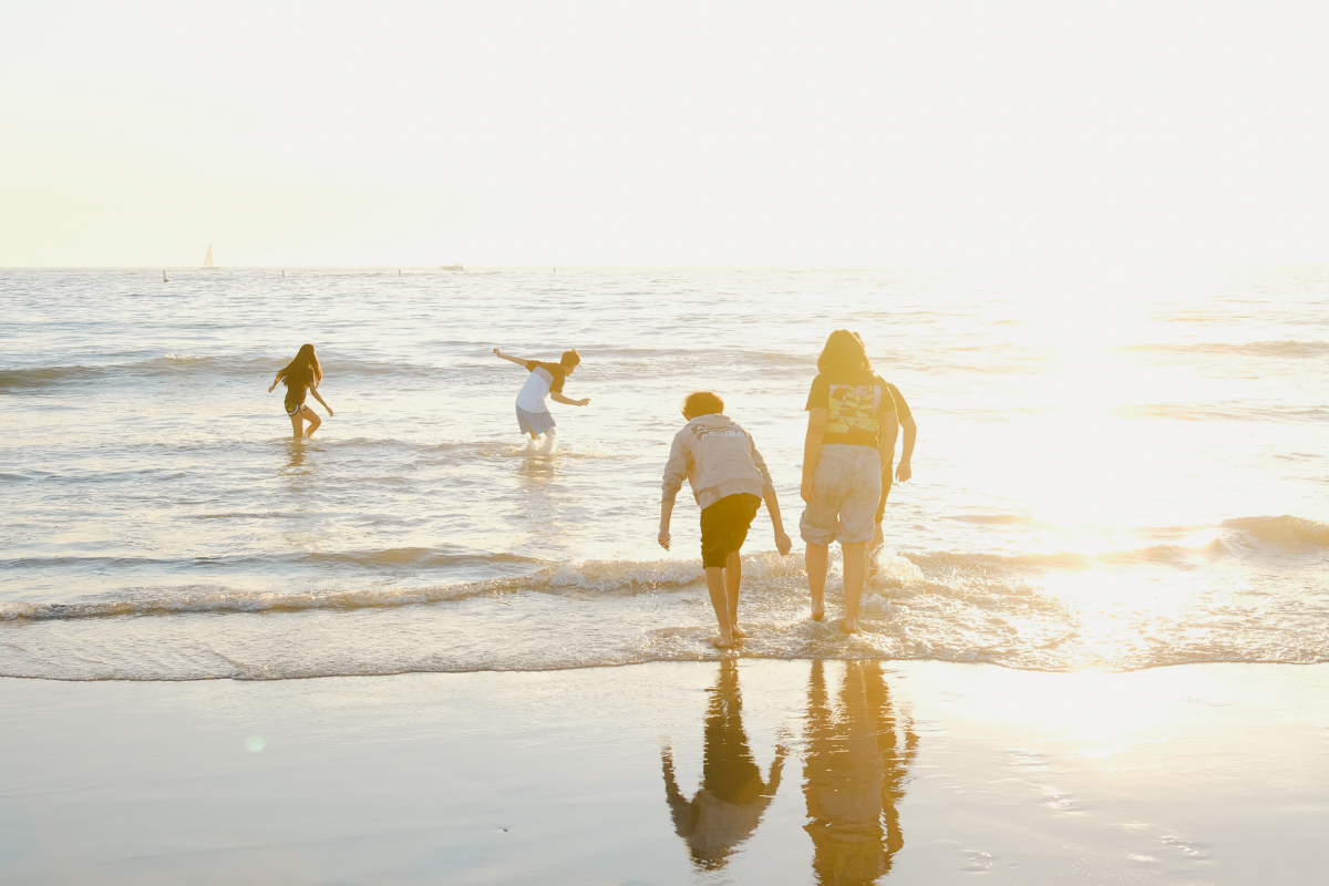 A family enjoying their time at the beach, kids running around by the shoreline watching the sunset
